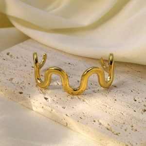 Gros plan détaillé du bracelet manchette doré ondulé poli sur fond de satin doux