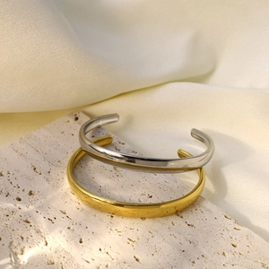 Détail de bracelets ouverts ondulés polis en or et argent sur pierre et tissu en soie