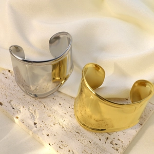 Brazaletes anchos pulidos en oro y plata sobre seda y textura de piedra natural