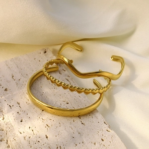 Vue détaillée d'un ensemble de trois bracelets dorés avec motifs vagues et coeurs