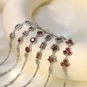 Detail showing vintage silver chain bracelet with various geometric emerald charms