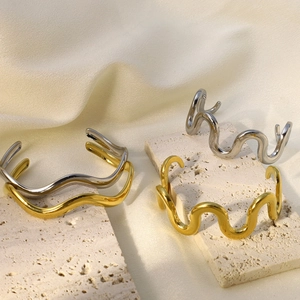 Bracelet jonc vague minimaliste doré et argenté sur support en pierre beige élégant