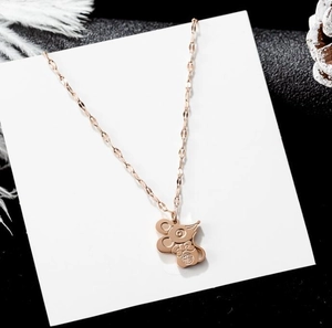 Gros plan du collier pendentif souris or rose avec caractère Fu sur carte et plume