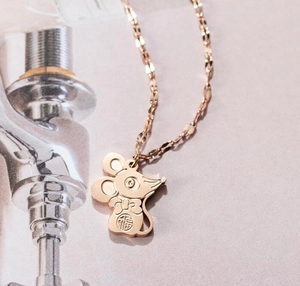 Gros plan du collier avec pendentif rat en or rose et caractère Fu sur magazine