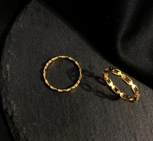 Detailed close-up of 18K gold-plated chain-link and textured hollow rings on stone