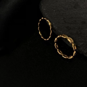 Minimalist chain link and geometric textured 18K gold plated titanium rings on black stone