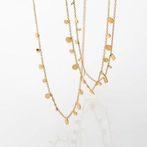 Layered gold geometric necklace with round and rectangular sequin charms on white backdrop