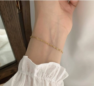 Close-up of a minimalist 18K gold plated twisted rope chain bracelet on a female wrist
