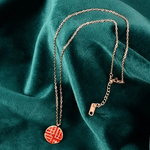 Dettaglio collana Fu in oro rosa con strass rossi e marchio K18 su velluto verde