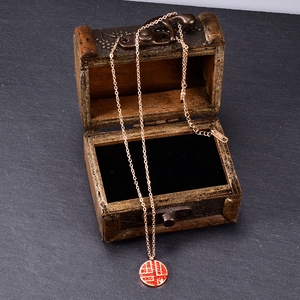 Dettaglio della collana Fu in oro rosa con cristalli rossi e marchio K18 su scrigno