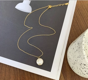Minimalist 18K titanium steel necklace with a single freshwater pearl on an aesthetic desk