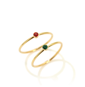 Detailansicht zweier minimalistischer 18K Goldringe mit roten und grünen Edelsteinen