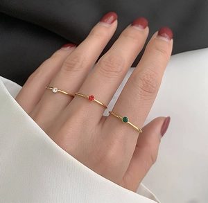 Detailansicht von drei minimalistischen 18K vergoldeten Ringen mit kleinen runden Edelsteinen