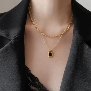 Zweilagige Goldhalskette mit schwarzem Rechteckanhänger und Figaro-Kette an einem Modell