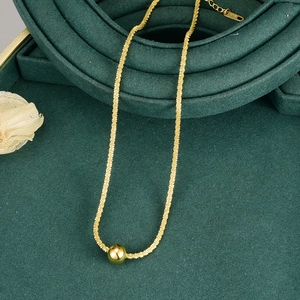 Close-up of golden ball pendant necklace with K18 stamp on deep green velvet background