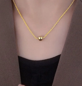 Detailed view of a shiny gold bead pendant on a sparkling titanium steel chain necklace