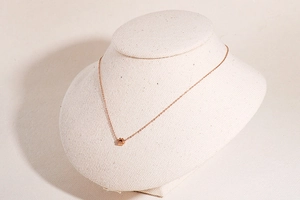 Collana minimalista in oro rosa con ciondolo a fiore traforato mostrata su un modello