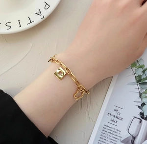 Close-up of a gold daisy chain bracelet with geometric charms on a woman's wrist