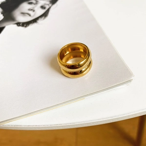 Polierter doppellagiger goldener Edelstahlring auf einem minimalistischen Hintergrund