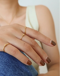 Nahaufnahme von drei minimalistischen 18K Goldringen mit fließenden Formen am Finger