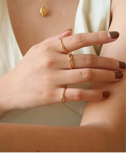 Detailansicht von 18K vergoldeten Ringen an der Hand mit warmem, metallischem Finish