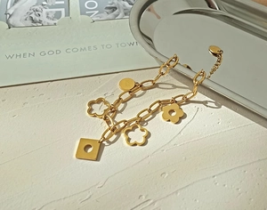 Macro shot of gold daisy flower charms and lucky tag on a thick chain bracelet