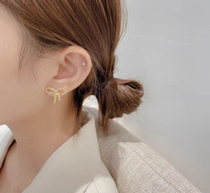 Gros plan sur d'élégantes boucles d'oreilles nœud en or 18K avec texture givrée