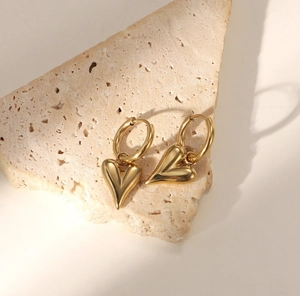 Golden heart drop earrings in polished stainless steel on a natural stone base