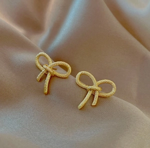Boucles d'oreilles nœud papillon en or 18 carats avec texture tressée sur fond en soie
