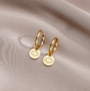 Chic gold Evil Eye dangle earrings with polished mirror finish on luxury champagne satin