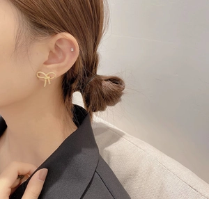 Détail de boucles d'oreilles nœuds dorées texturées portées par un mannequin