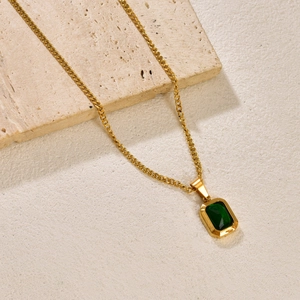 French emerald pendant necklace in 18k gold plating shown on a textured background