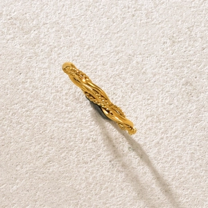 Detailansicht des goldenen geflochtenen Rings mit gedrehter Textur auf Steinhintergrund