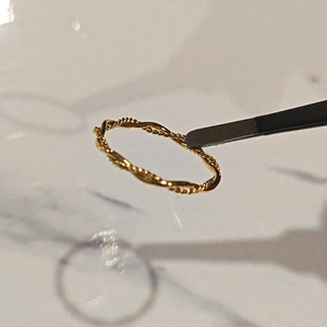 Minimalistischer doppellagiger gedrehter Seilring aus Gold-Titanstahl auf Marmor