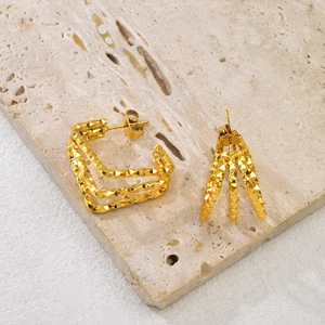 Close-up of golden multi-layer square earrings with diamond-cut sparkling texture