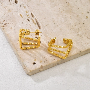 Macro detail of triple-layer gold geometric square earrings with diamond-cut texture finish