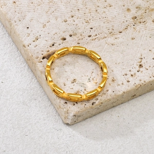 Detailansicht des goldenen Edelstahl-Kettenrings auf einem beigen Travertin-Stein