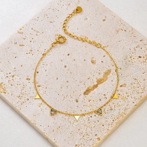 Detail view of 18K gold geometric bracelet with triangle charms on natural stone
