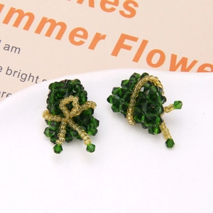 Macro shot of handmade beaded green rice dumpling earrings with gold bow details
