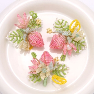 Dettaglio di ciondoli a fragola e foglie in perline fatti a mano per gioielli DIY