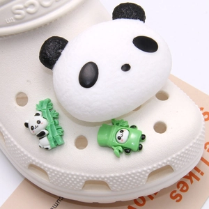 Close-up of 3D panda shoe charms set on white clogs featuring cute bamboo panda designs