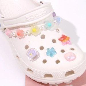 Dettaglio dei fiori in resina colorata, perle e ciondoli a stella per scarpe tipo sabot