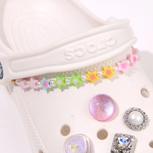 Detail view of macaron stars and pearls chain on clogs with glitter and heart charms