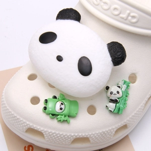 Macro view of cute panda charms and green bamboo accessories on white clog shoes