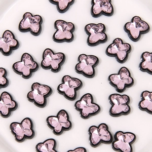 Vue détaillée de strass papillon rose en résine avec bordures en alliage noir