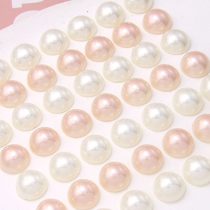 Flache Darstellung von cremefarbenen und rosa Perlenimitaten für DIY-Schmuckherstellung