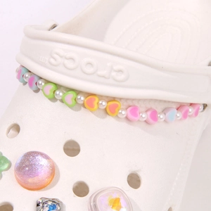 Detail of macaron heart beads and pearl charms on white clogs for summer beach style