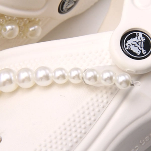 Detail view of white clog shoes with elegant faux pearl chain and small pearl charms