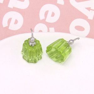 Macro shot of green resin jelly pudding earrings on a white porcelain tray