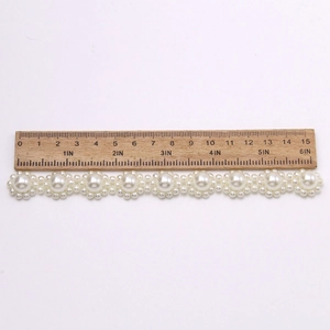 Detail shot of daisy-shaped pearl shoe charms and trim with measuring ruler scale